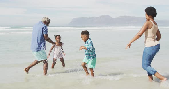 Happy african american couple playing with children on sunny beach