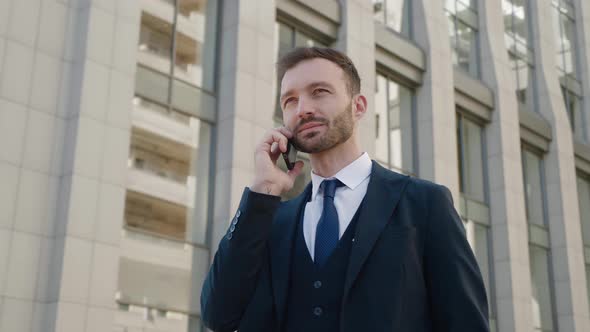 Portrait of Confident Businessman in Classical Suit Talking on Phone Outdoors at Business District