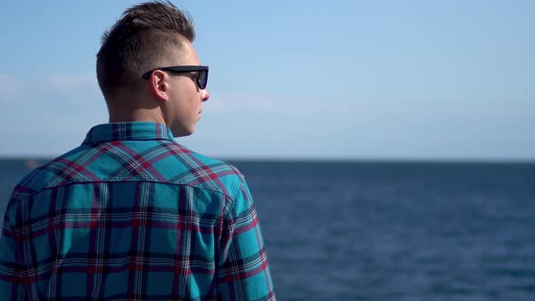 A Young Man Looks at the Sea. A Man in a Blue Shirt Admires Nature. A Man Stands with His Back To