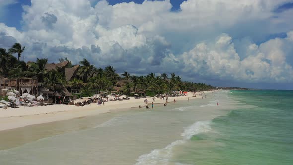 aerial drone of tourists on a tropical Tulum beach in the hotel zone during a sunny day with turquoi