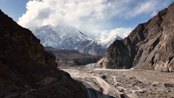 Drone Flying Through Shadow Of Valley To Reveal Snow Capped Mountains Of Hunza Valley. Dolly Forward