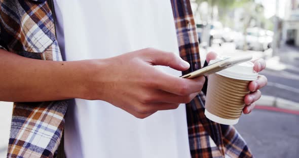 A man texting and drinking coffee