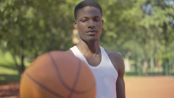Middle Shot of African American Man Stretching Ball To Camera and Smiling