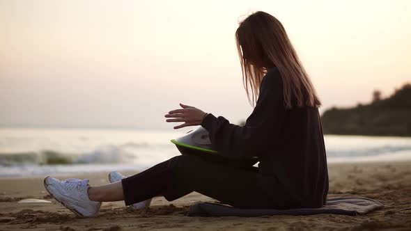 The Girl Playing Hang Sitting on the Beach in Front the Sea Alone