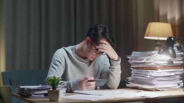 Asian Man Being Upset Losing Game On Smartphone After Working With Documents At Home