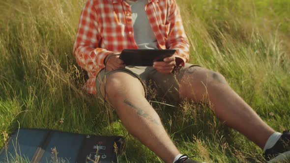 Handsome African American Man Networking on Tablet Pc Powered By Solar Charger in Nature