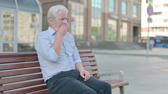 Old Man Coughing While Sitting Outdoor on Bench