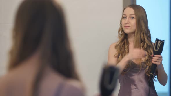 Portrait of Female Using Curler Near the Mirror