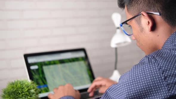 Rear View of Young Man Using Laptop on Office Desk