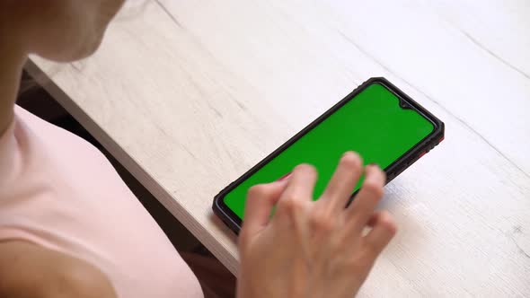 A Girl During a Manicure Uses a Smartphone with a Green Screen