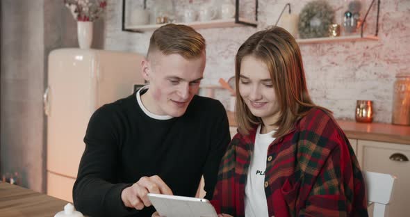 A Guy and a Gitl Are Watching a Funny Videos at the Kitchen. 