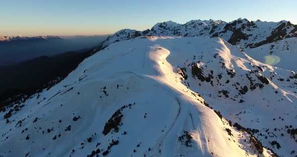 Downhill ski track at the Chamrousse French Alps during sunrise, Aerial dolly out shot