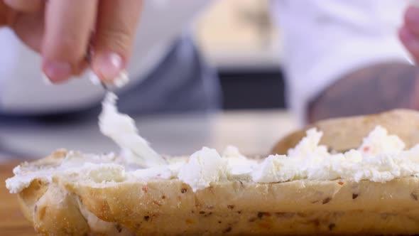 male chef spreads cream cheese on crunchy bun prepare sandwich. sandwich cooking