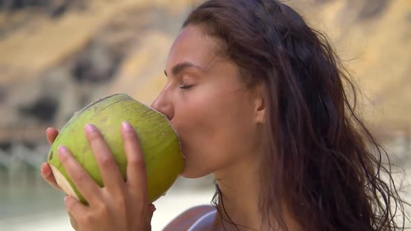 Close Up Shot of Attractive Brunette Girl Drinking Coconut Water on the Paradise Beach