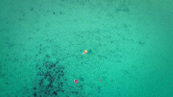 High aerial view of two young girls swimming and playing in sea with inflatables.