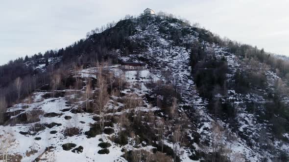 Moving Up Above Pine Woods Forest and Snowy Mountain in Autumn or Winter at Sunset