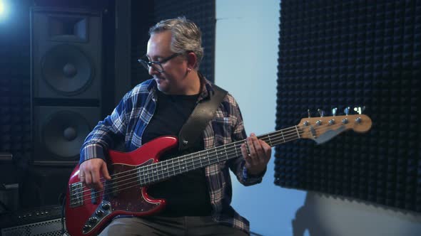 Portrait of Mature Man Playing Red Bass Guitar