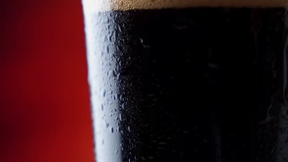 Dark Beer Closeup. Pint of Cold Craft Beer Rotation. Glass of Beer with Water Drops.