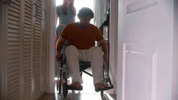 Man in a Wheelchair Trying to Pass the Hallway and His Wife Following Him