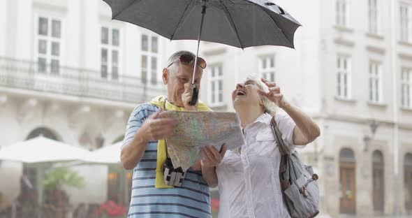 Happy Senior Tourists Stand Downtown and Enjoy the Rainy Weather in Lviv