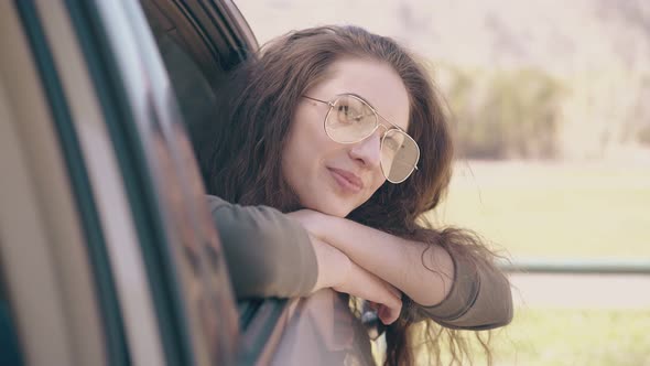 Pretty Dreaming Woman in Glasses Looks Out of Auto Window