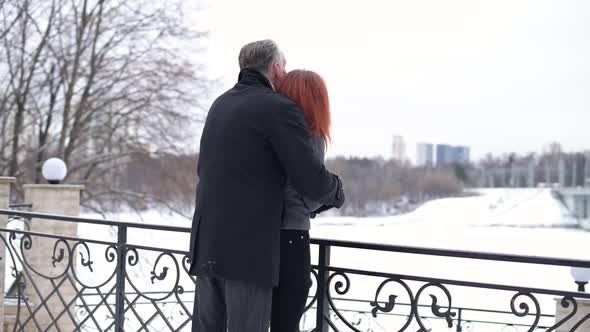 Back view of a man and a woman hugging in the park in winter