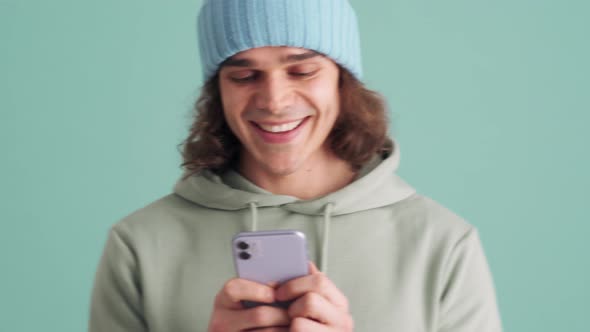 Positive man in blue hat texting by phone