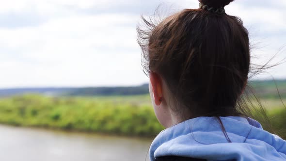 Woman Stands at the Edge Looks Ahead at a Large River the Wind Blows Her Hair