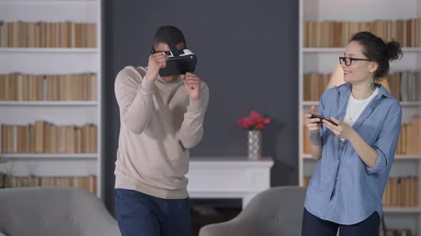 Young African American Man in VR Headset Having Fun Boxing in Augmented Reality and Laughing