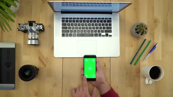 Flat Lay Of Man Hands Using Phone With Green Screen At Workplace