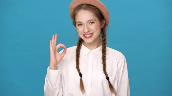 Horizontal Portrait of Cheerful Candid Woman Isolated Over Blue Background Wall Showing Ok Sign and