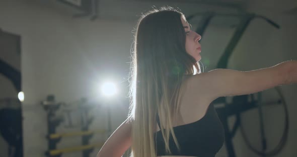 Young Girl in Sportswear Warmsup Arms and Torso During Work Out in a Gym