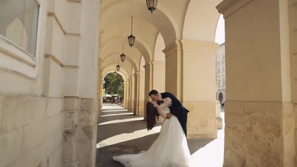 Newlyweds Portrait Caucasian Groom Bride Hugging Embracing Kissing on City Street Wedding Couple