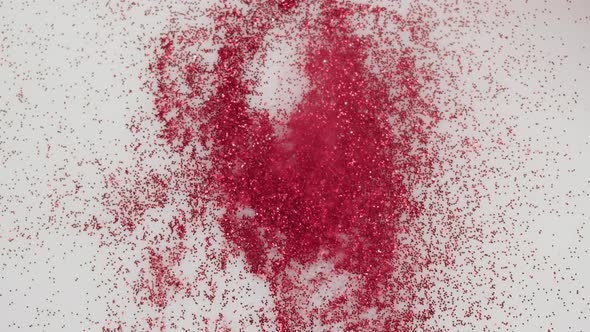 Pouring Red Glitter on White Background Gloss Powder Closeup