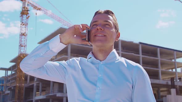 Business person standing in front of construction site. Office building and crane.