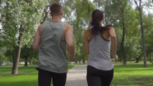 Back View of Couple Running in Park on Summer Day