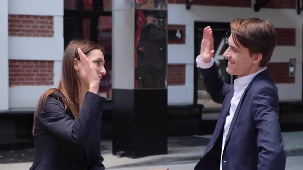 a young couple sit on a bench and chat, high-five each other