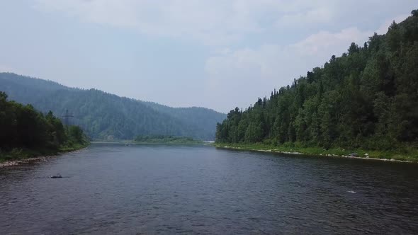 Drone Flies Over River in Mountainous Countryside.