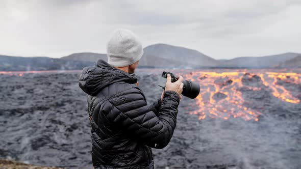 Photographer Looking Through Camera To Flowing Lava In Landscape