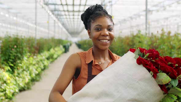 Happy African American Woman with Roses in Flower Greenhouse