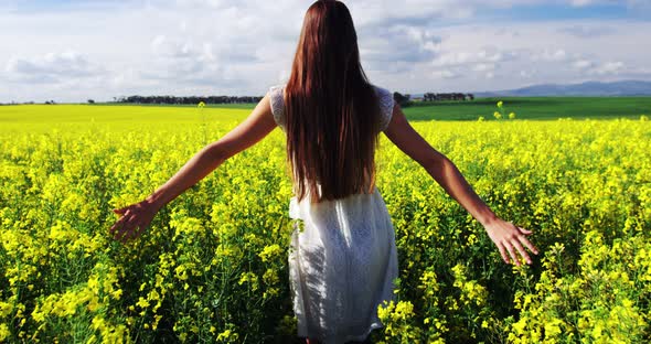 Woman touching flowers while walking in field