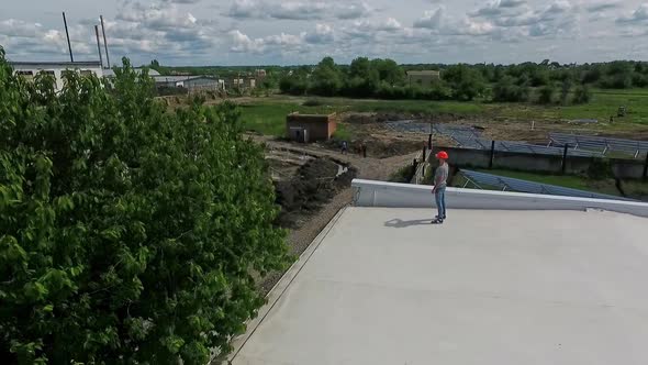 Technician in orange hard hat on a roof in summer