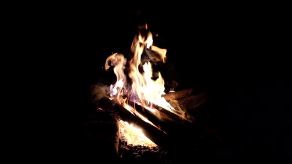 A campfire with sparks flying around in the dark night