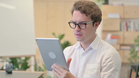 Portrait of Young Man Celebrating on Tablet in Modern Office