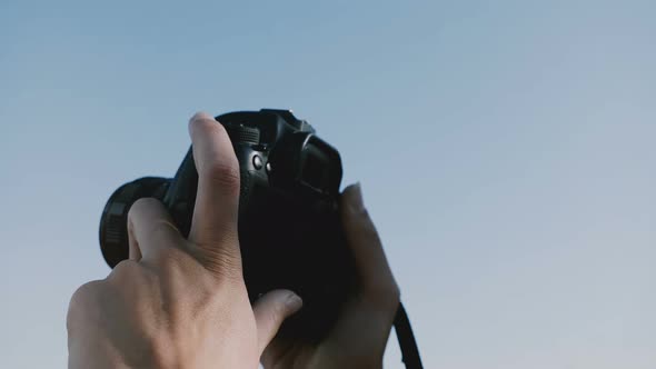 Close-up Shot of Two Photographer Hands Holding a Digital Photo Camera Up Outdoors on a Sunny Clear