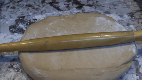 Thin Rolling Pin Being Used To Flatten Out Fresh Dough On Table. Locked Off