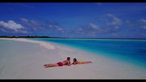 Boy and girl relax on idyllic resort beach break by blue green lagoon with white sand background of 