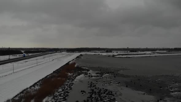 Snowy Field Beside The Highway On A Cloudy Day. aerial