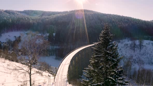 Curving single rail train viaduct in winter mountains in evening sun.