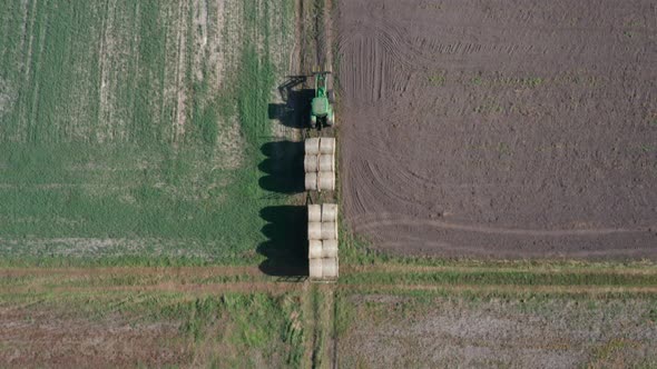 Agricultural aerial shot of a tractor driving through the fields, with an  attached carriage of larg